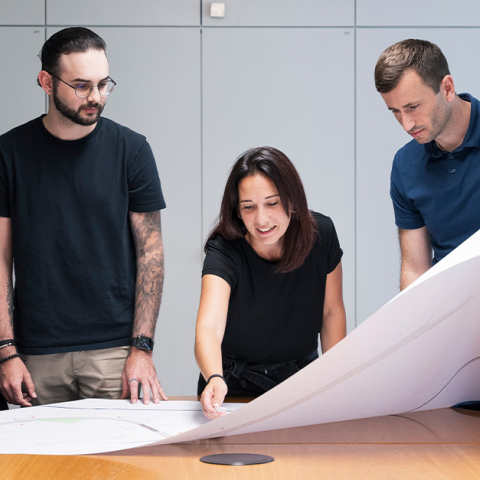 Drei Mitarbeiter diskutieren einen Plan im Büro