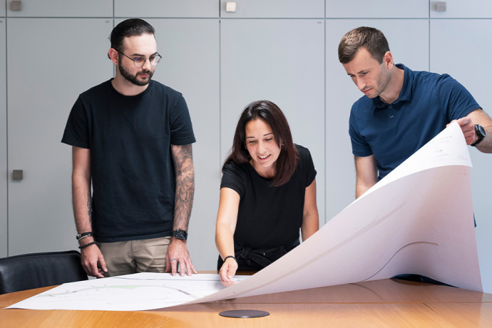 Drei Mitarbeiter diskutieren einen Plan im Büro