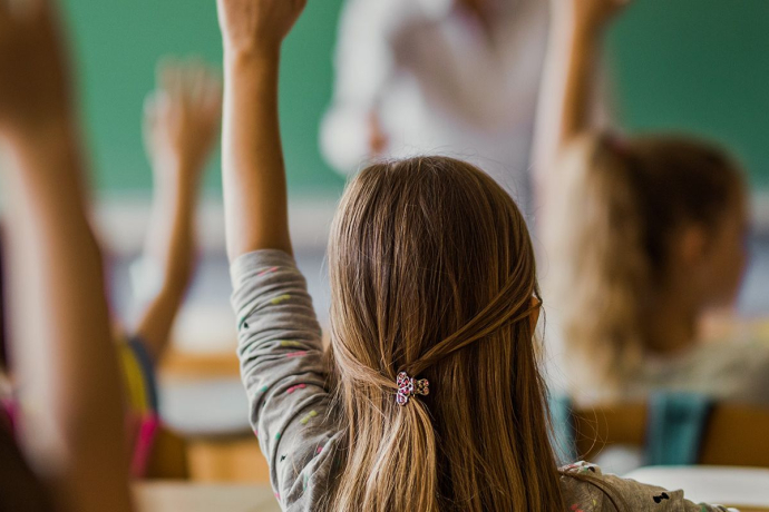 Kinder in der Schule heben die Hände